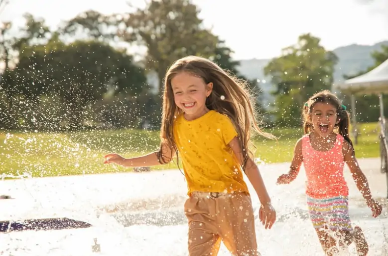 Two girls playing and running through the water in summer.