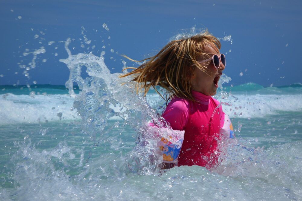 Girl emerges from water very excited.