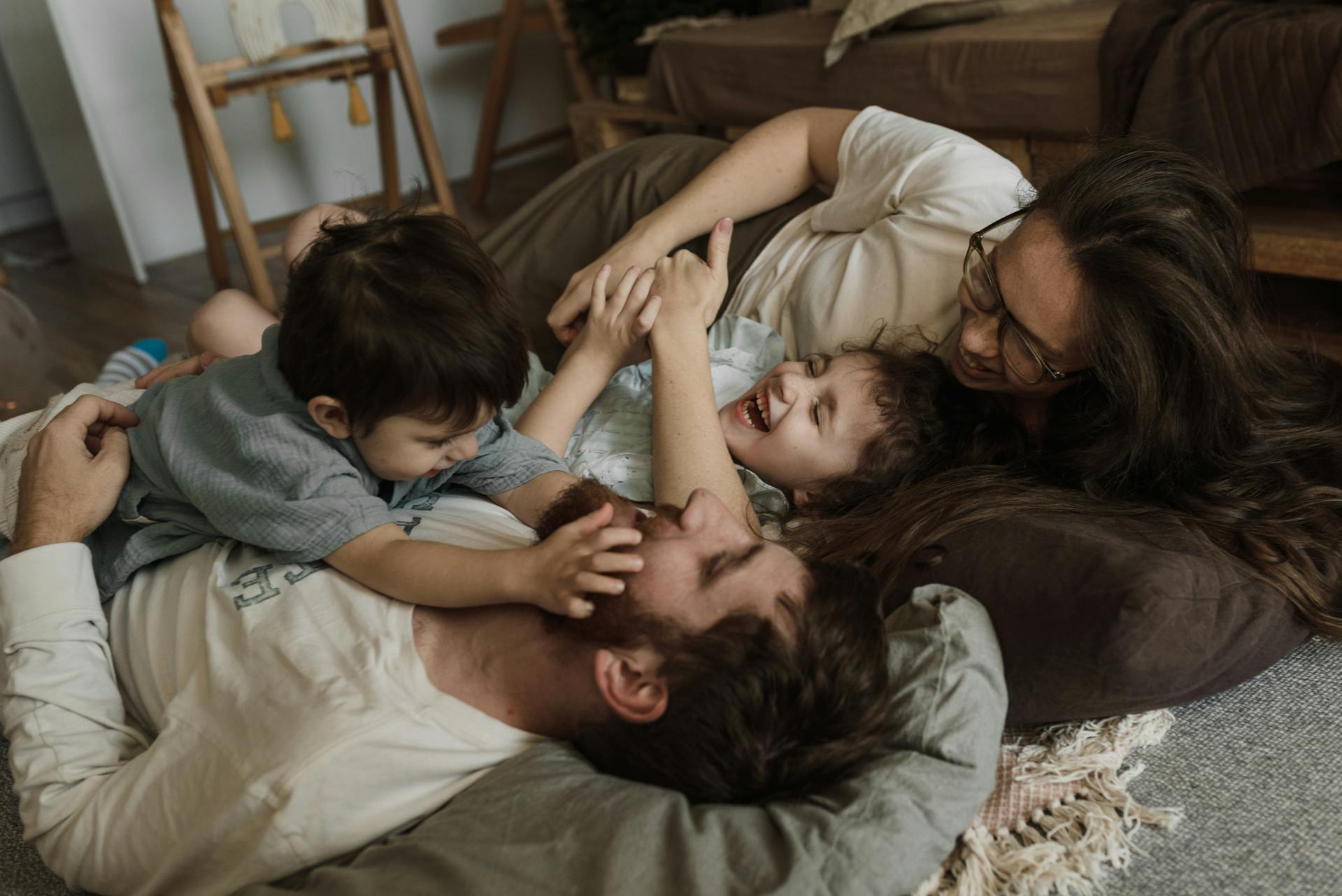 A family of four lay together laughing and playing.