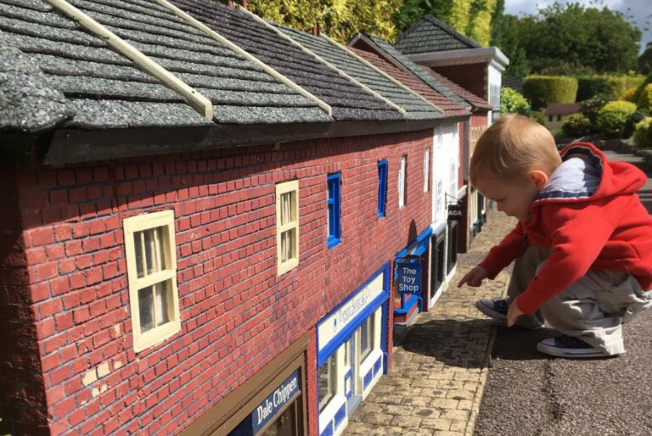 Young boy peers into the windows of a model village